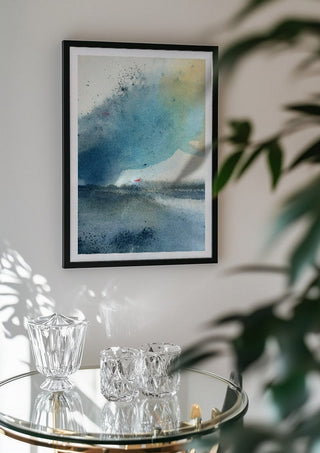 Blue October by Tania Zubareva in a black frame above a glass table with crystal glassware