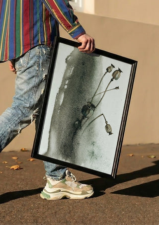 Death by Tania Zubareva carried in a black frame along a sunny street