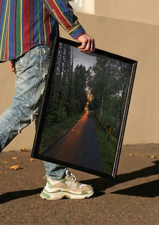 The Amber Forest Path by Bora Kőhalmi carried in a black frame along a sunny street