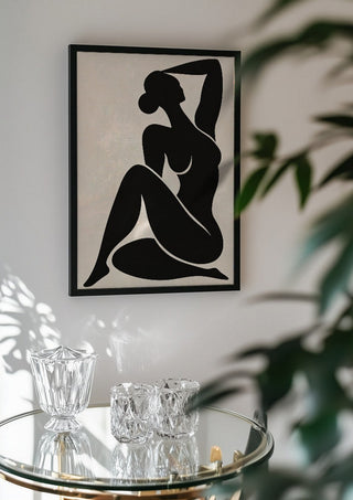 Abstract Black Nude Woman by TimlessArtworks in a black frame above a glass table with crystal glassware