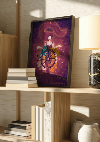 Wheel of Fortune by Sciurus tarotus in a dark frame on a wooden shelf beside books and a lamp