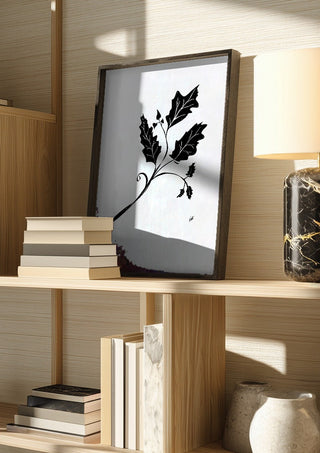 Leife by FridaRit in a dark frame on a wooden shelf beside books and a lamp