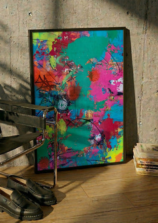 paint it loud by hazelart in a black frame leaning against a concrete wall by a steel chair