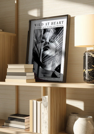 unleafed by hazelart in a dark frame on a wooden shelf beside books and a lamp
