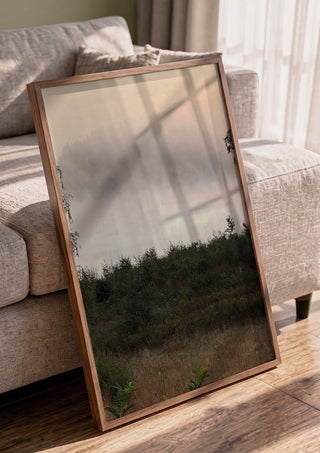 När älvorna dansar by Ljilja Marinic in a walnut frame leaning against a grey sofa