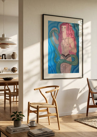 Eva in Paradise by Carmen Coduri in a black frame in a bright dining room with wooden chairs