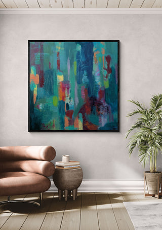 Beginnings by Janet Bell in a black frame above a tan leather sofa beside a potted palm