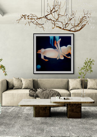 Contact #2 by Luis Valquaresma in a black frame above a pale sofa under a branch chandelier