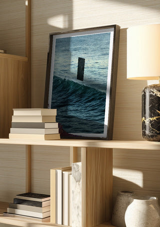 Deep Blue by Fran Rodriguez in a dark frame on a wooden shelf beside books and a lamp