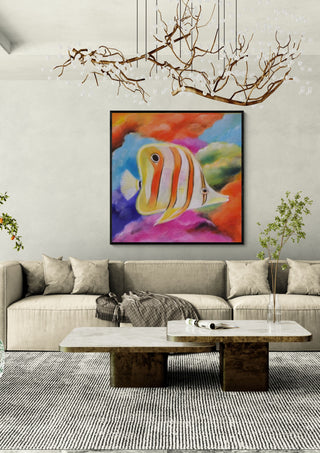 Happy Fish by Sunny in a black frame above a beige sofa under a branch chandelier