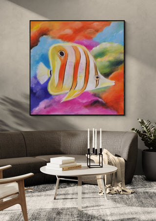 Happy Fish by Sunny in a black frame above a grey sofa with a round table and candlesticks
