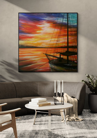 Sunset in red by Sunny in a black frame above a grey sofa with a round table and candlesticks