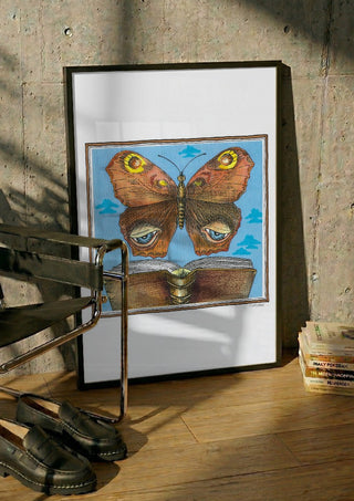 The Butterfly and the Book by Waldemar Mandzel in a black frame leaning against a concrete wall by a steel chair