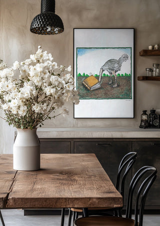 The Ostrich and the Book by Waldemar Mandzel in a black frame above a rustic table with white flowers