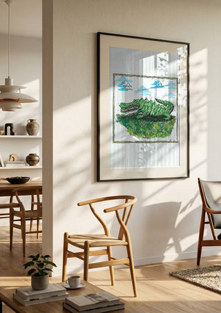 The Crocodile and the Book by Waldemar Mandzel in a black frame in a bright dining room with wooden chairs
