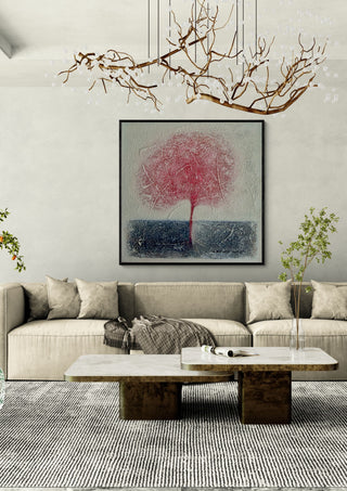 Red Tree by Marina Agre in a black frame above a beige sofa under a branch chandelier