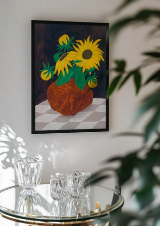 Gula blomster på rutig duk by Rebecka Hansson in a black frame above a glass table with crystal glassware
