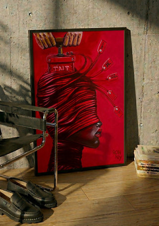 TNT by Ronny Simon in a black frame leaning against a concrete wall by a steel chair