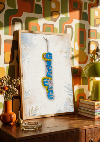 GREECE Terracotta by Ammar in a wooden frame on a sideboard against retro patterned wallpaper