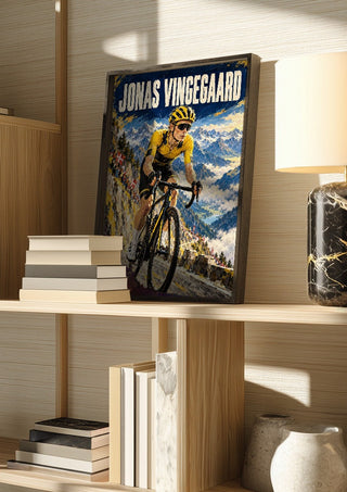 Jonas Vingegaard by Danii Steinfeldt in a dark frame on a wooden shelf beside books and a lamp