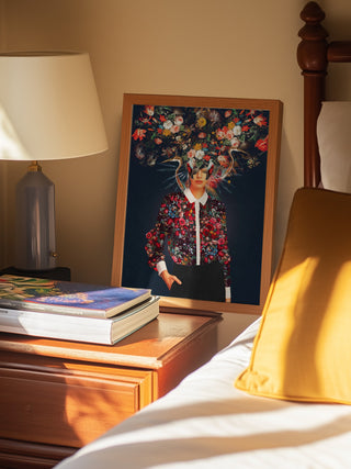 Framed "Your Head Was Full of Colours That Had No Names" by Frank Moth on a bedside table next to books and a lamp.