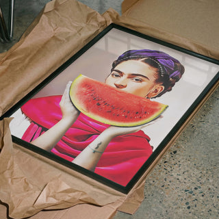 Framed "Watermelon Frida - Dikhotomy" art print featuring Frida holding a watermelon, unboxed on brown paper.