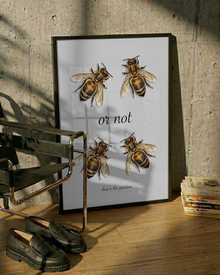 Framed "To Bee Or Not" poster by Andreas Magnusson featuring bees and text, leaning against a wall.