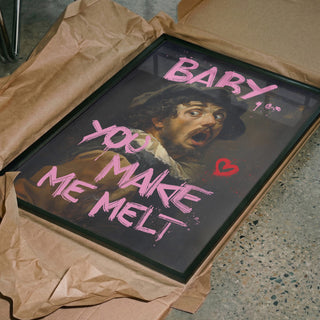 Framed artwork with text "BABY YOU MAKE ME MELT" in pink over a classical portrait, shown on brown wrapping paper.