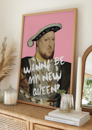 Framed art of King Henry VIII with "WANNA BE MY NEW QUEEN?" text, displayed on a wicker console.
