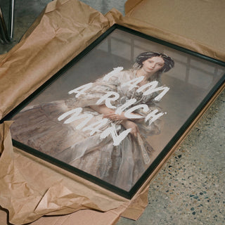 Framed portrait of an elegant woman with the text "I Am A Rich Man" by Talitha McQueen, on brown wrapping paper.