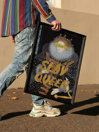 Person holding the Slay Queen Portrait - Talitha McQueen in a black frame while walking outdoors.