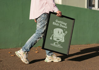 Person holding a framed Getting Things Done Roll by Andreas Magnusson, featuring a cartoon roll character.