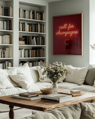 Neon artwork reading "call for champagne" by Andreas Magnusson displayed in a cozy living room above a sofa.
