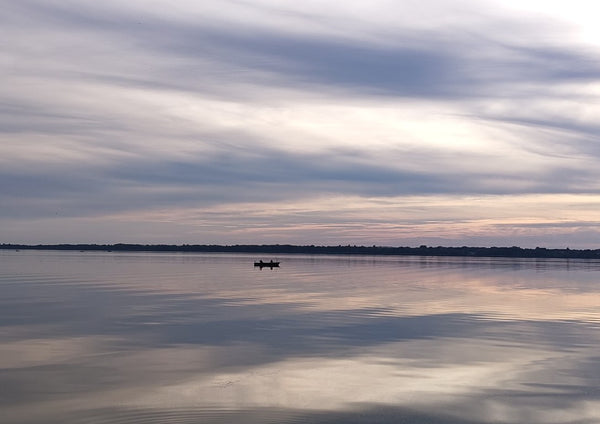 Dusk Reflections by Bora Kőhalmi - banded dusk clouds mirrored in the still water of Lake Balaton with a small boat on the horizon