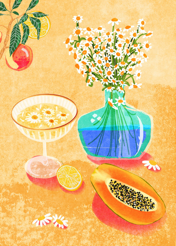 A vase of daisies, a cocktail, papaya, and citrus decorate a table in Summer Day Vibes by Raissa Oltmanns.