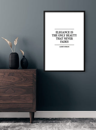 Framed "Elegance is the only beauty that never fades" quote poster on a dark wall above a wooden dresser.