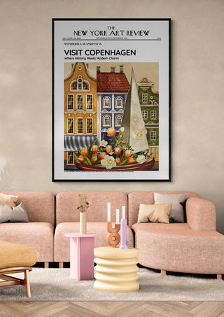 Framed "Copenhagen - Art Review Plakat" poster above a modern pink sofa in a stylish living room.