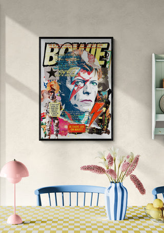 Framed Bowie - Ricardo Noble artwork featuring a colorful portrait on a wall above a table with flowers.