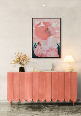 Framed "Sunrise Birds" by Martina Karlsson above a peach sideboard with decor, lamp, and flowers.