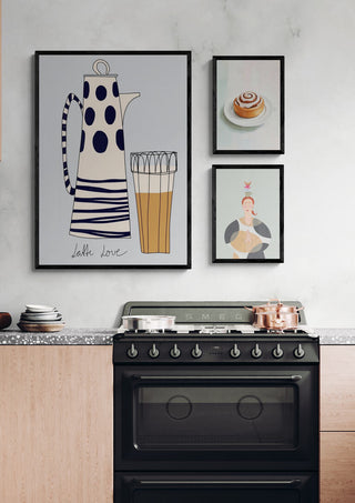 Modern kitchen with oak cabinets, black stove, and playful framed art on a light gray wall above the countertop.