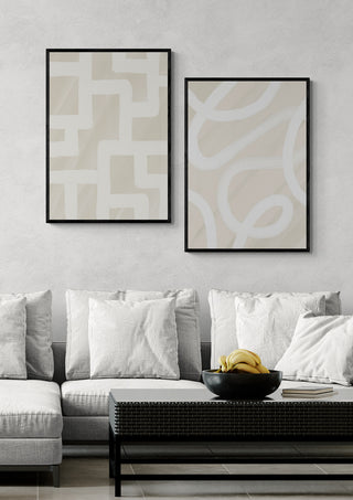 Two Quiet Structure - Yuli abstract prints in black frames hang above a modern sofa with light cushions.