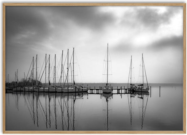 Warten auf den Wind by Guido Lucker - black and white photograph of sailing boats at a jetty reflected in calm water